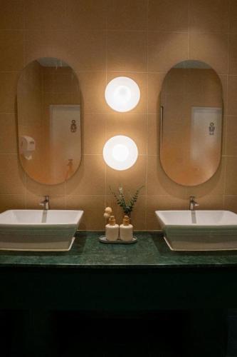 a bathroom with two sinks and two mirrors at 777Bliss Hometel in Nakhon Phanom