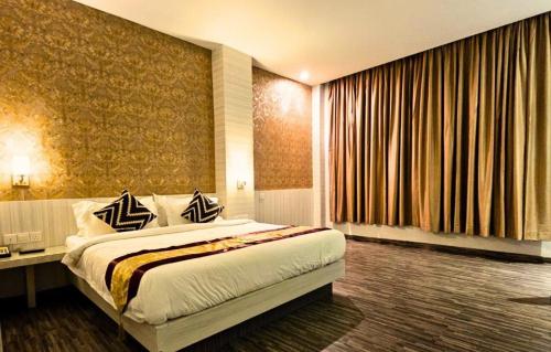a hotel room with a bed and a large window at Alltrue Sydney Hotel Batam Center in Batam Center