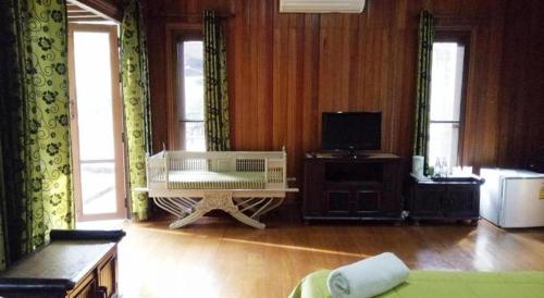 a living room with a white couch and a tv at Indie House @ Maerim in Chiang Mai