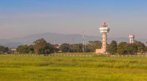 a grass field with a lighthouse in the distance at So Herbs at Home in Chiang Rai