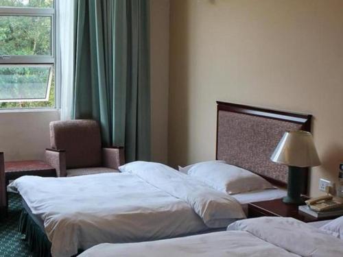 a hotel room with two beds and a chair and a window at Traders Inn Brunei in Bandar Seri Begawan