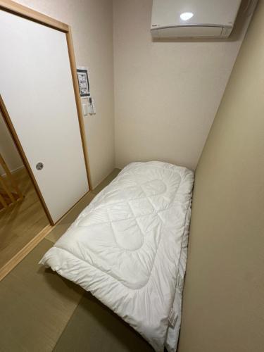 Wadaにある宇凪院-千本北の小さな客室で、角に白いベッドが備わります。