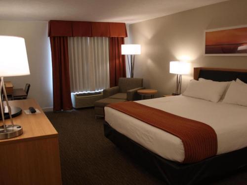 a hotel room with a large bed and a chair at Holiday Inn Express Munising-Lakeview Hotel By IHG in Munising