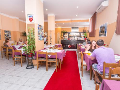 people sitting at tables in a restaurant with a red carpet at Villa Valentina in Zadar