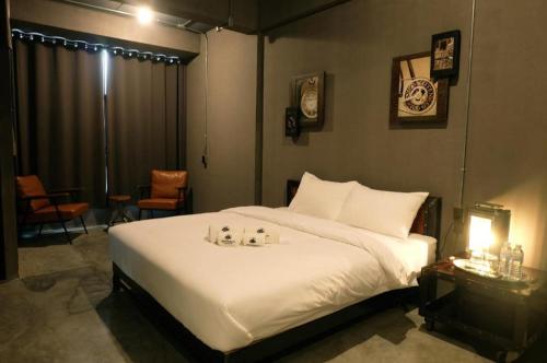 a bedroom with a white bed with two candles on it at Rider bedroom hostel & cafe in Hua Hin