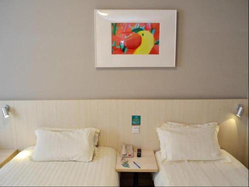 a bedroom with a bed and a table with a picture on the wall at Jinjiang Inn Nanjing Xinjiekou in Nanjing