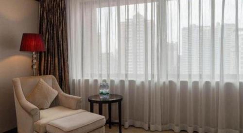 a living room with a chair and a window at SUN Yat-sen university Hotel and Conference Centre in Guangzhou