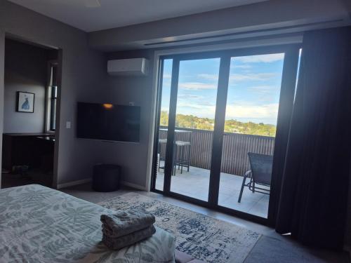 a bedroom with a large glass door leading to a balcony at RESIDENTIAL 4 BEDROOM House in Coffs Harbour