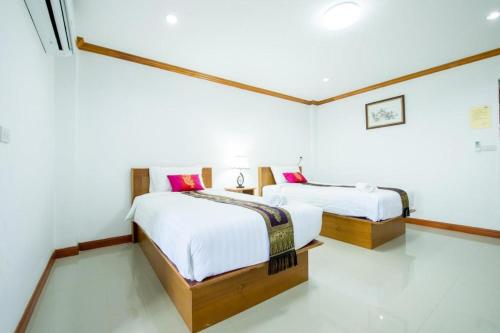 two beds in a room with white walls at Thatphanom View Hotel Nakhon in Nakhon Phanom