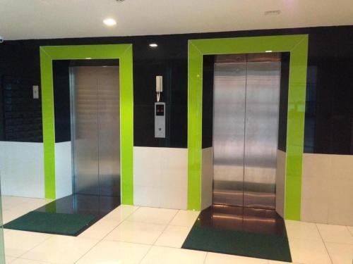 two elevators in a building with green and silver at Ipremium Sukhumvit 81 Hotel in Bangkok