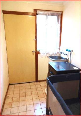 a kitchen with a door and a sink and a stove at Charming Three-Bedroom Holiday Home Near Tourist Attractions in Werribee