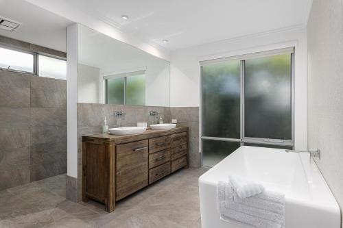 a bathroom with two sinks and a large window at Vogue Design Footpath to the beach in Busselton