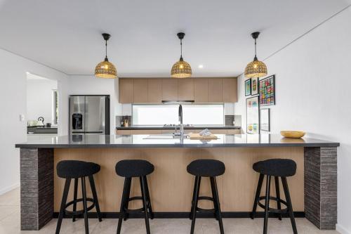 a kitchen with three bar stools at a counter at Vogue Design Footpath to the beach in Busselton