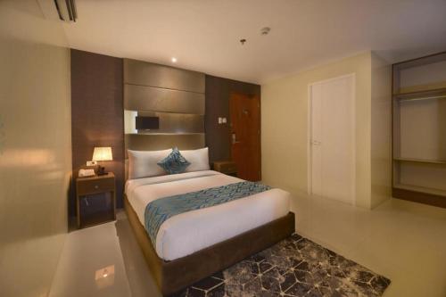 a bedroom with a large bed and a night stand at Hotel Estrella in Tacloban