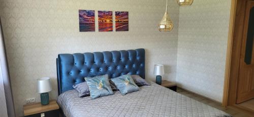 Bett mit blauem Kopfteil in einem Schlafzimmer in der Unterkunft Apartamentai AGNIJA in Kretinga