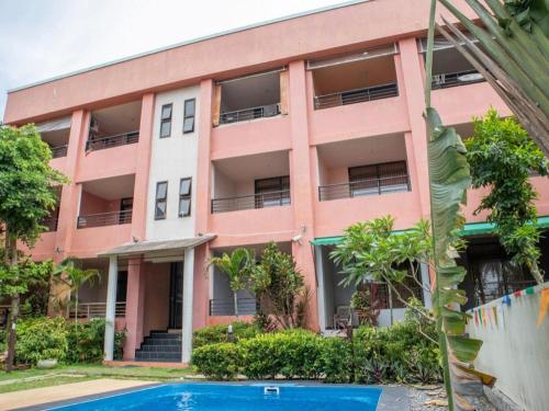a pink building with a swimming pool in front of it at OYO 567 U Residence in Ban Lamai