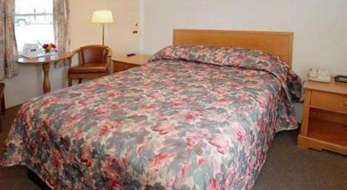 a hotel room with a bed with a floral bedspread at Rodeway Inn in Rutland
