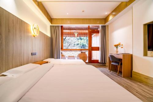 a bedroom with two beds and a desk at Wuxing Qinglan Homestay in Houhong