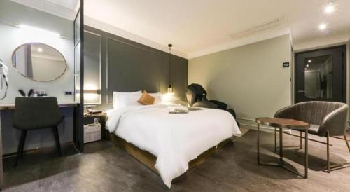 a bedroom with a bed and a desk and a mirror at Cheongju Maryjane Hotel in Cheongju