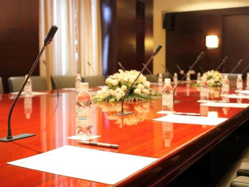 a long wooden table with two microphones and flowers at Kunshan Newport Hotel in Suzhou