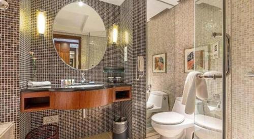 a bathroom with a sink and a toilet and a mirror at Kunshan Newport Hotel in Suzhou