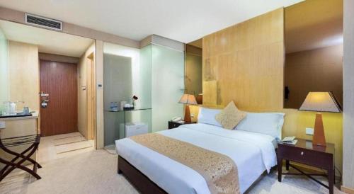 a bedroom with a large white bed and a desk at Golden Central Hotel Shenzhen in Shenzhen
