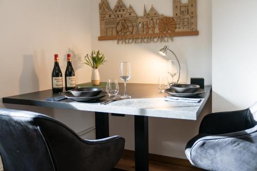 a table with wine glasses and wine bottles on it at MEHA Appartment Paderborn in Paderborn