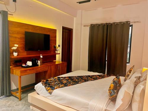a bedroom with a bed and a desk and a television at Hotel Aura Residency , Haridwar in Haridwār