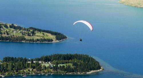 a person flying a kite over a body of water at Oaks Queenstown Club Suites in Queenstown