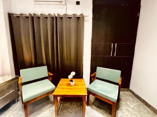 two chairs and a table in a room with a curtain at Hotel Aura Residency , Haridwar in Haridwār