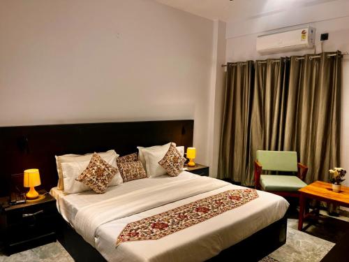 a bedroom with a large bed and a green chair at Hotel Aura Residency , Haridwar in Haridwār