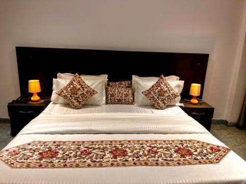 a bedroom with a large white bed with pillows at Hotel Aura Residency , Haridwar in Haridwār