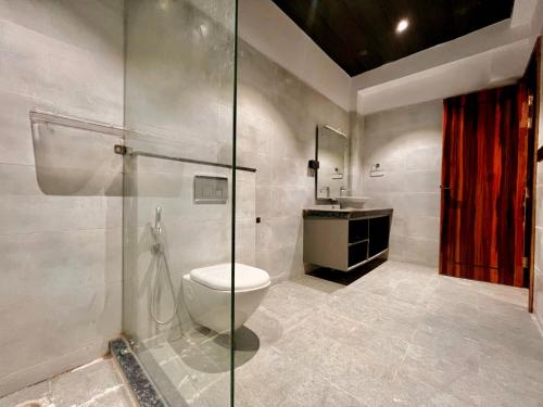 a bathroom with a toilet and a glass shower at Hotel Aura Residency , Haridwar in Haridwār