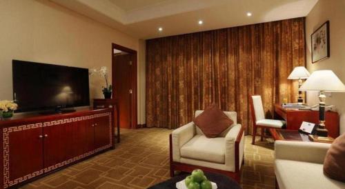 a living room with a couch and a television in a hotel room at Capital Hotel in Beijing