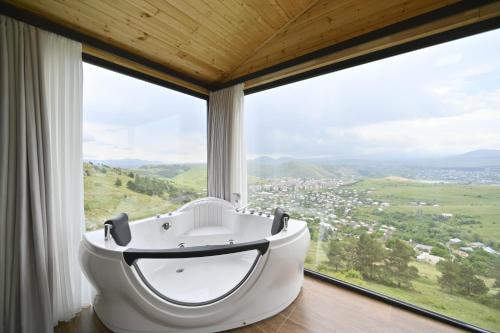 a bath tub in a room with a large window at Stonehenge Hotel & Restaurant in Tsaghkadzor