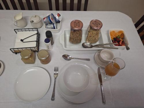 a table with white plates and utensils on it at Oude Post Guesthouse and Cottage - The Old Postmaster's House in Lydenburg