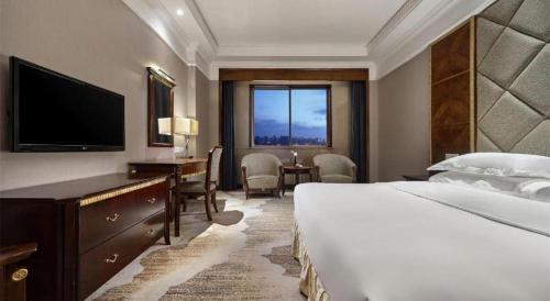 a hotel room with a bed and a desk and a television at New Century Hotel Taizhou 