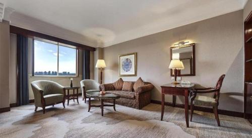 a living room with a couch and a table and chairs at New Century Hotel Taizhou 