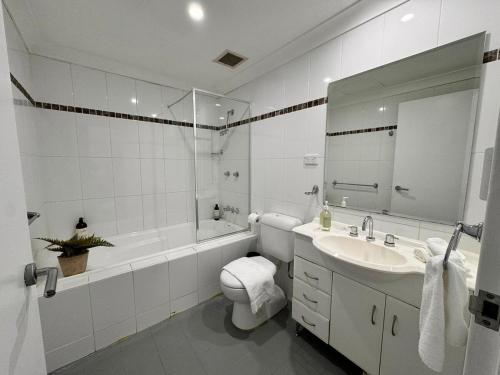 a bathroom with a sink and a toilet and a tub at Modern 2-Bedroom Apartment 7mins to Paramatta Train Station in Sydney