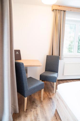two chairs and a table in a room with a window at Hotel Alpina in Kleinarl