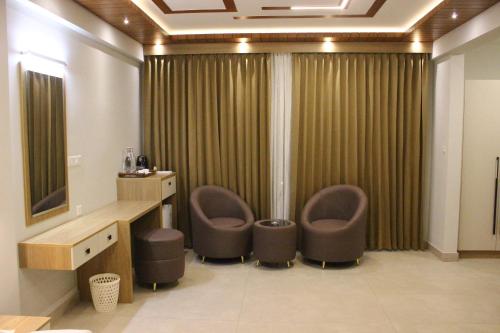 a bathroom with two chairs and a sink and a mirror at Cozycaza resort in Padinjarathara