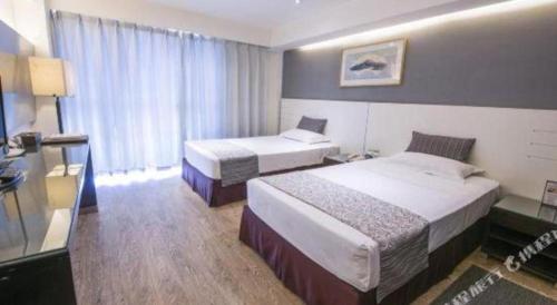 a hotel room with two beds and a window at Tianjin Juchuan Lily Hotel in Binhai