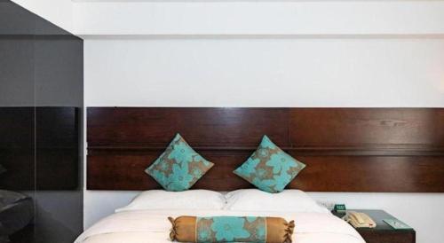 a bed with a wooden headboard and pillows at Tianjin Juchuan Lily Hotel in Binhai
