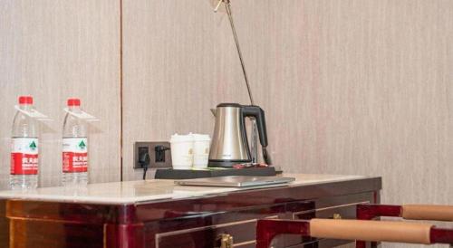 a table with a kettle and two bottles of soda at Metropolo Hotel Yining Development Zone Hanma Building in Kipekyüzi