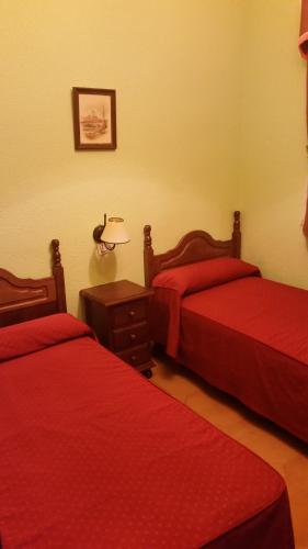 a room with two beds with red sheets and a lamp at Hidalgo in Alcaudete