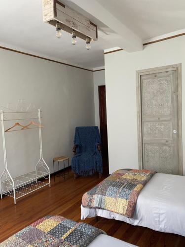 a bedroom with two beds and a blue chair at La Casa Verde B&B in Trivero
