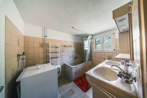 a bathroom with a tub and a sink and a bath tub at ALPINEMAGIC Chalet Wartstein in Grindelwald