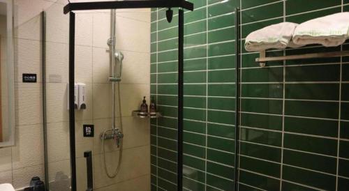 a bathroom with green tiled walls and a shower at GreenTree Inn Yichun Mingyueshan Airport in Yichun