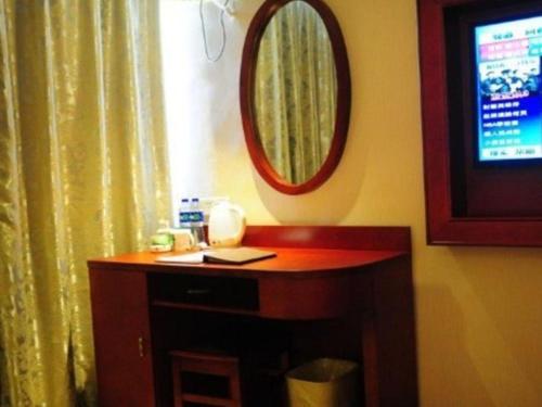 a room with a table with a mirror and a television at GreenTree Inn Ganzhou Sankang Temple DaRunFa Express Hotel in Ganzhou