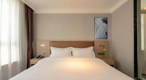 a bedroom with a large white bed in a room at GreenTree Inn Ganzhou Sankang Temple DaRunFa Express Hotel in Ganzhou